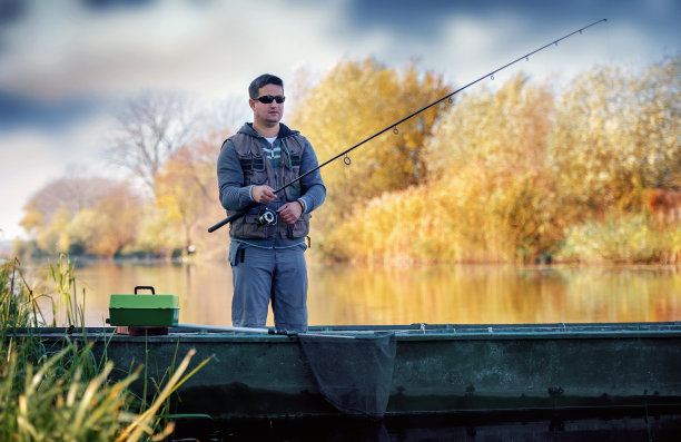 渔夫站在船上，在河上垂钓。体育及康乐概念图片下载