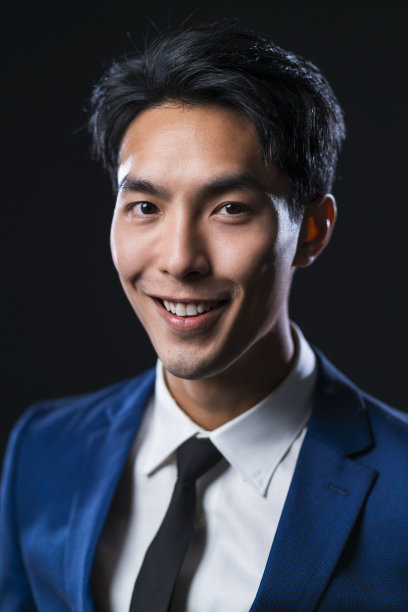有吸引力的亚洲男性的肖像穿着正式的西装脸积极的表情工作室拍摄与黑暗的背景，亚洲商务人士看着相机isolare黑色的背景图片下载