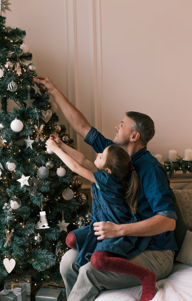 平安夜，爸爸和女儿在家装饰圣诞树。等待假期图片下载