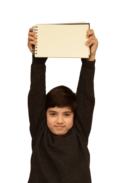 从一名男生的垂直照片上剪下来，他穿着整洁的白领衬衫，深灰色的毛衣或套头衫，双臂直举，看着相机，拿着空白的螺旋形记事本，在白色的背景上孤立地显示出来图片下载