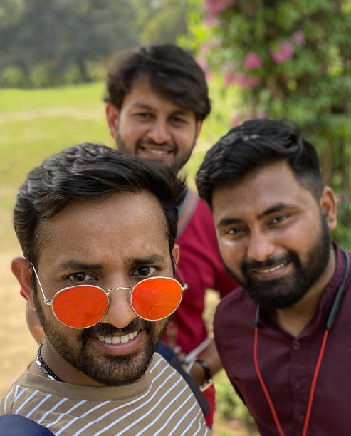 在一个阳光明媚的日子里，印度的家人和朋友在公园户外拍摄的照片，微笑着看着相机自拍，一个戴着墨镜的男人，聚焦在前景上图片下载