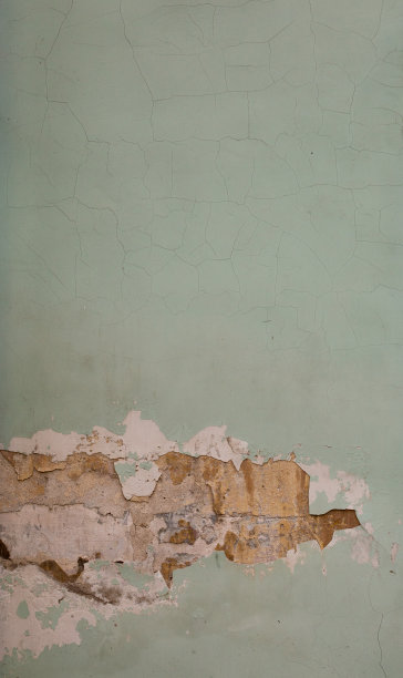 旧的浅绿色油漆，肮脏，划伤，破旧的灰泥墙和黄砖的裂缝。垂直照片背景图片下载
