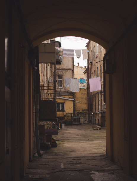 一座通往奥德萨古老庭院的拱门。阳光明媚的春天大气照片与古老的庭院，破旧的房子，肮脏的划痕的墙壁和晾晒的亚麻和衣服图片下载