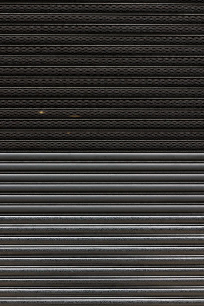 一扇灰色和黑色的旧金属车库门的一部分图片下载