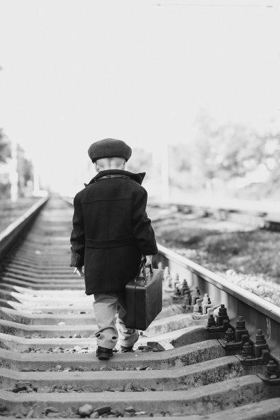 黑白复古照片，一个孩子带着行李箱走在枕边图片下载