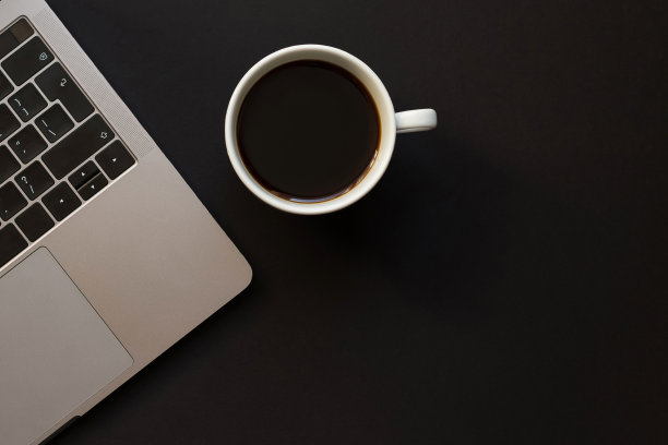 一张黑色的桌子，一台笔记本电脑和一杯咖啡。图片下载