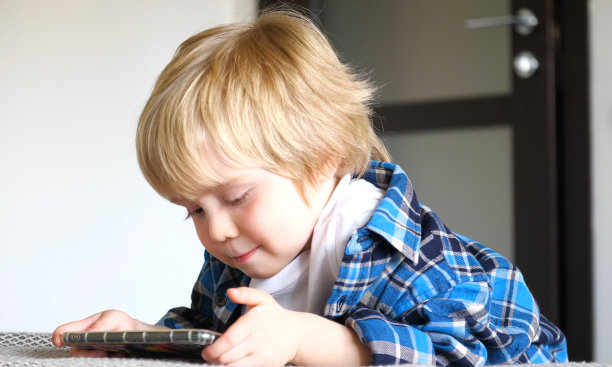 小男孩在床上玩智能手机图片下载