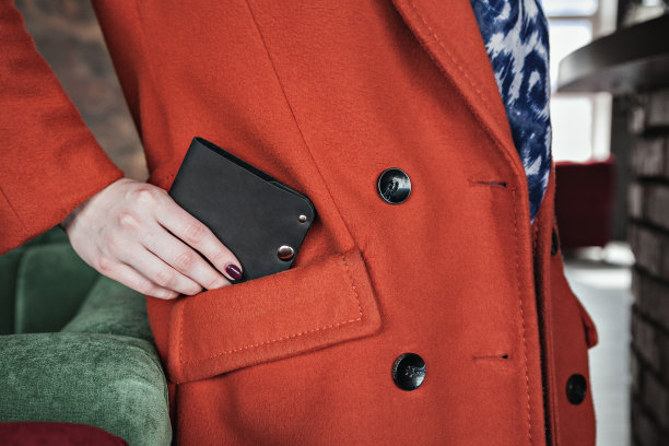 一个穿红色外套的女孩手里拿着一个钱包图片下载