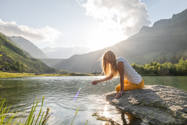 从高山湖中舀水的年轻女子图片下载