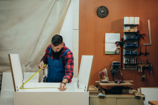 年轻男性木匠在车间工作，用仪表测量图片下载