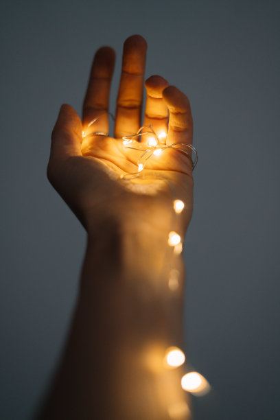 魔法就在你的手中。一根闪闪发光的圣诞花环在你的手中，温暖的圣诞心情，柔和的焦点图片下载