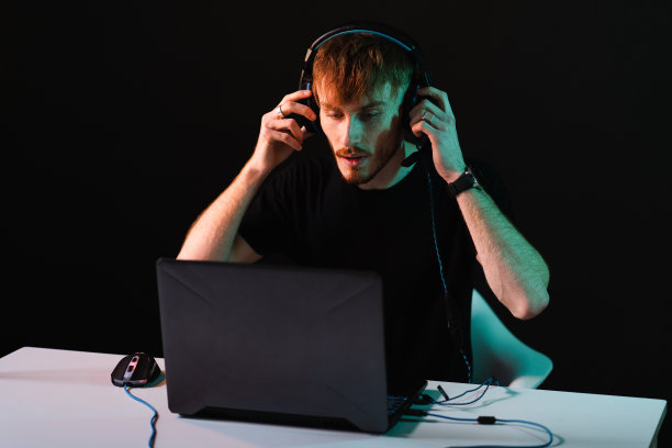 在霓虹灯背景下戴着耳机玩电子游戏的玩家图片下载