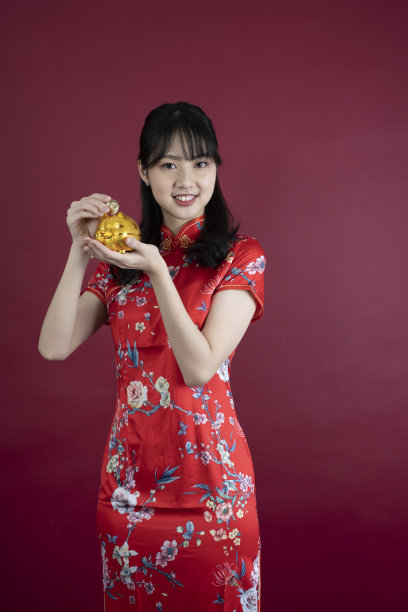 快乐的亚洲年轻女子展示黄金储蓄罐庆祝中国新年图片下载