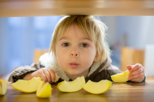 可爱的小男孩，吃着绿苹果片图片下载
