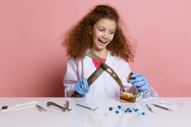 小女孩的漫画肖像，孩子在牙科医生的形象穿着白色的实验外套和手套孤立在粉红色的工作室背景图片下载