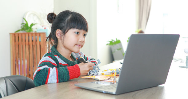 小亚洲女孩在房子里的科学课上建造机器人汽车。它促进了天才儿童的发展，提高了他们的学习技能。图片下载