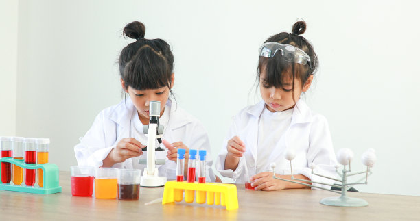 小女孩亚洲可爱的小学生学习研究和做化学实验，在家里的桌子上用试管分析和混合液体。图片下载