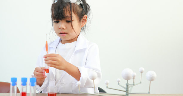 小女孩亚洲可爱的小学生学习研究和做化学实验，在家里的桌子上用试管分析和混合液体。图片下载