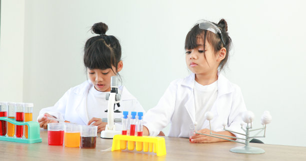 小女孩亚洲可爱的小学生学习研究和做化学实验，在家里的桌子上用试管分析和混合液体。图片下载