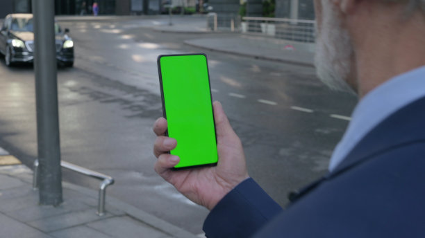 老商人使用智能手机与绿色屏幕，户外图片下载
