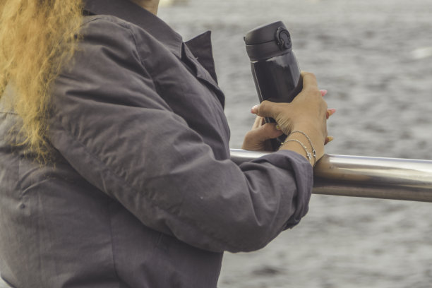 堤岸上那个手里拿着热水瓶的女孩望着大海图片下载