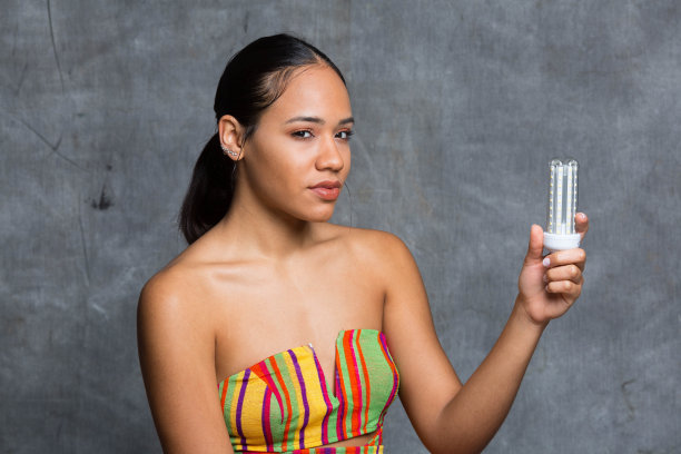 小女孩手里拿着节能灯泡，节约用电图片下载