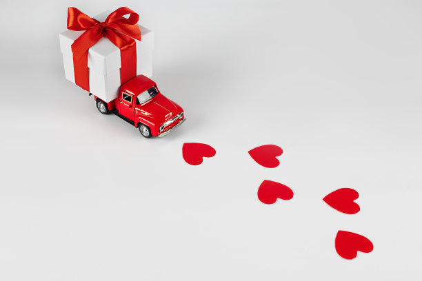 红色轿车，白色背景上的礼品盒。概念-送礼物的节日，情人节，国际妇女节，2月14日，3月8日。购物、销售图片下载
