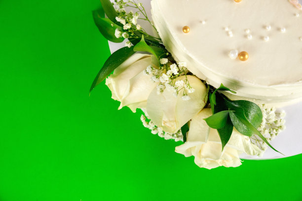 绿色背景上白玫瑰的生日蛋糕。图片下载