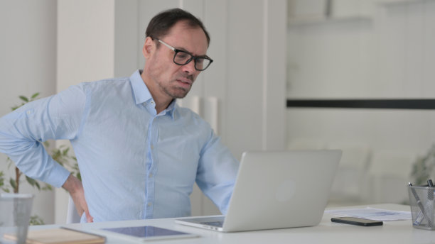 中年男子在办公室使用笔记本电脑时背痛图片下载