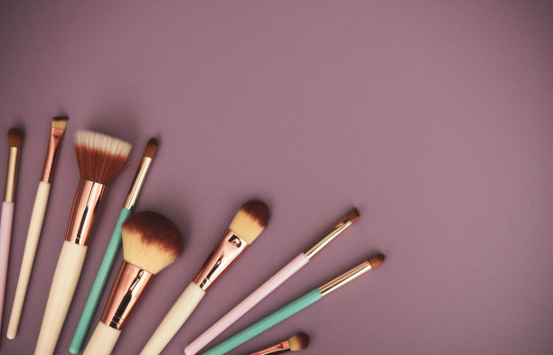 粉红色的背景与各种各样的化妆笔刷与复制空间。头顶球图片下载