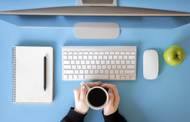 俯视图，女性手在电脑前工作，蓝色背景。图片下载