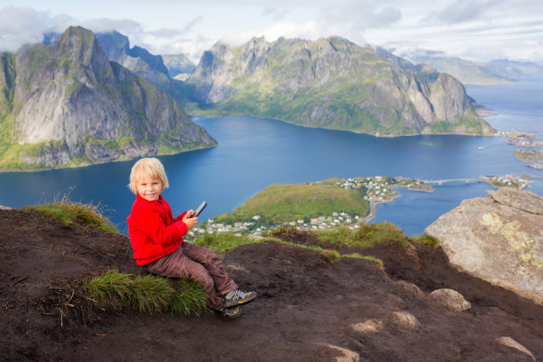 可爱的孩子，在爬完有很多楼梯的Reinebringen徒步小径后，坐在山顶俯瞰Reine图片下载