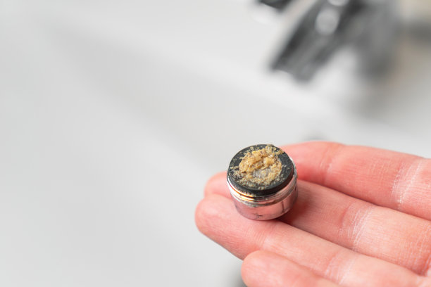 脏污堵塞的卫生间龙头，手放在曝气器上方的水槽里。自来水过滤器。钙渣图片下载