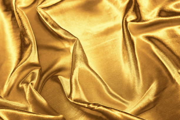 金色织物背景，波浪形黄色纹理。奢华的丝滑面料。图片下载