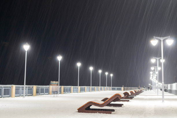 冬天的傍晚，在这个海滨小镇的木板路上，空荡荡的躺椅躺在雪下图片下载