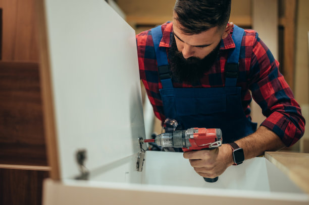 年轻男性木匠在车间使用电钻工作图片下载