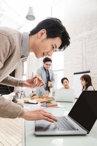 年轻的商人一边工作一边吃披萨图片下载