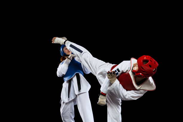 两个年轻女性的动态肖像，跆拳道运动员一起训练孤立在黑暗的背景。运动的概念，技能图片下载