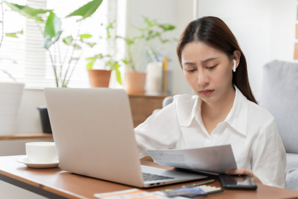 有吸引力的年轻女子使用笔记本电脑在家里工作。图片下载