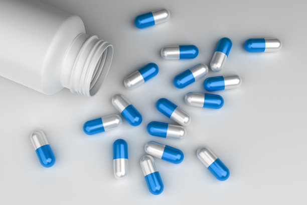 蓝色和白色胶囊药丸从塑料药瓶在白色背景俯视图。图片下载