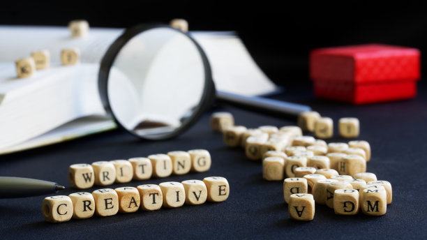 创意书写字母旁边打开教科书、放大镜、钢笔和红色礼品盒。文理学院创意写作与教学的概念。选择性聚焦图片下载