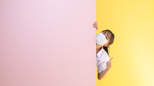 女学生戴着黄色和粉色背景的面具。图片下载