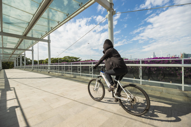 女人在阳光明媚的一天骑自行车在城市图片下载