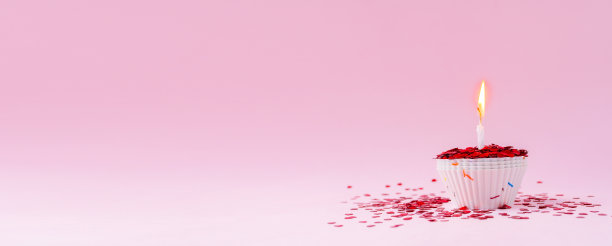 闪亮的节日纸杯蛋糕，粉红色的背景上燃着蜡烛。节日贺卡。情人节，母亲节，妇女节。图片下载