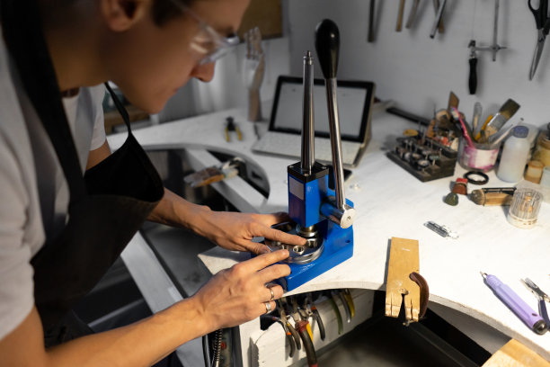 特写的戒指。珠宝首饰增加和减少戒指的工具。男子把戒指戴在工具上。模糊的前景。图片下载