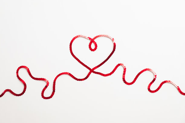 红丝带做成的心放在白色的桌子上。情人节快乐的概念。图片下载