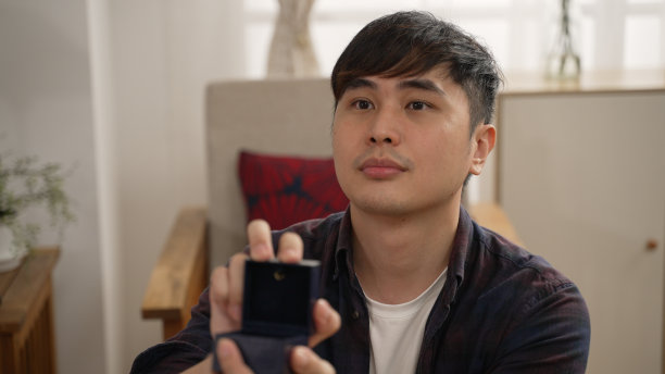 亚洲男子在家里展示求婚盒子里的戒指的肩部照片。他向女友求婚，并真诚地向她承诺图片下载