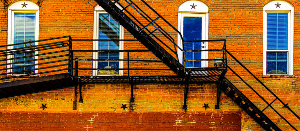 旧的西部拱形窗户小巷消防逃生楼梯在一个旧的褪色的砖建筑图片下载