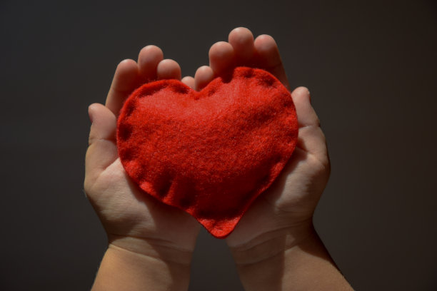 黑色背景上，孩子的手掌上有一颗心图片下载