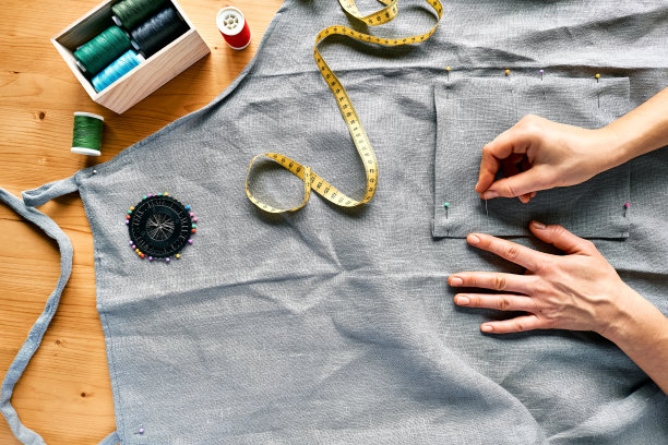 女人在给亚麻布料量尺寸。女裁缝在小工作室的缝纫机上缝纫。时尚工作室，裁缝，手工制作服装概念。慢时尚自觉消费图片下载